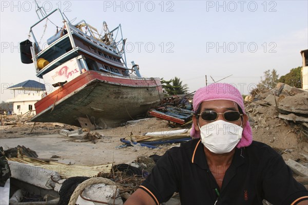 THAILAND, Phang Nga District, Nam Khem, "Tsunami. A volenteer takes a break from the clean up of the damage caused by the tsunami, nothing is left standing in the village, where 2500 people are pressumed dead, 125kms north of Phuket on the 2nd Jan."