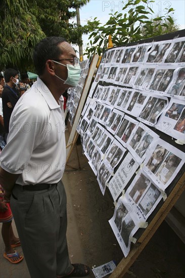 THAILAND, Phang Nga District, "Takua PA,", "Tsunami. Thai's look at the pictures of the unidentifeid dead posted up outside the temple, Wat Yan Yao. On the 31st Dec"