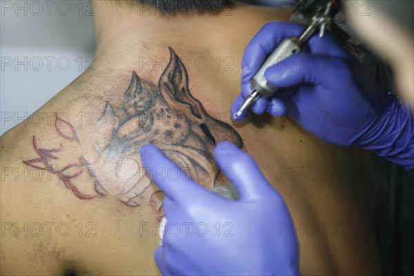 THAILAND, Phuket, Man having tattoo applied to her shoulder.