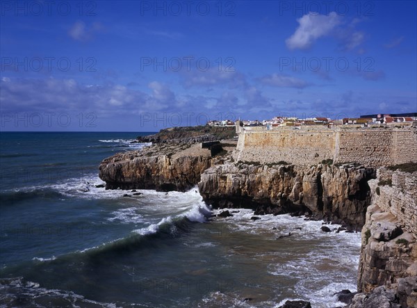 PORTUGAL, Estremadura, Ribatejo, Peniche. Atlantic Ocean town. Sea and cliffs topped by part of curtain wall to the 16th Century Fortaleza Castle situated south of the town.