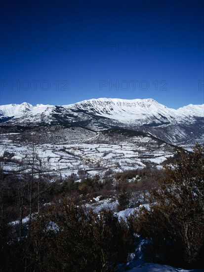SPAIN, Aragon, Pyrenees, Snow covered mountain Macizo de Posets which is 3369 metres 11033 feet high point. The border with France on the right skyline. Trees in the foreground.