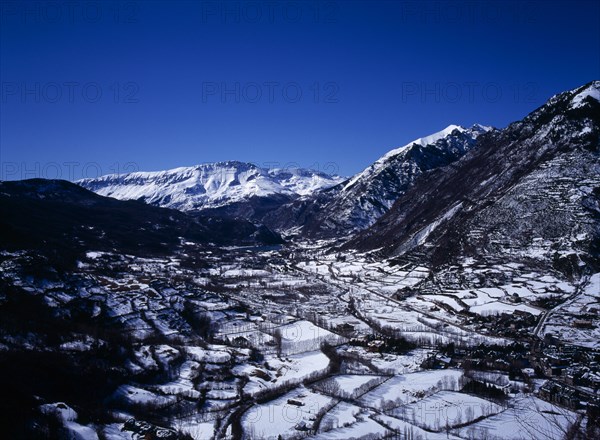 SPAIN, Aragon, Pyrenees, Elevated view south west along Rio Esera with snow covered valley and mountains. The town of Benasque seen on the lower right corner.
