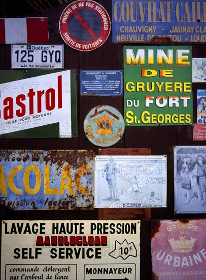 FRANCE, Indre et Loire, Chinon, A collection of enamelled advertising signs seen on a garage door. Small blue and white sign which refers to Somerset and Dorset Railway.