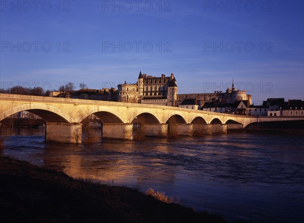 FRANCE, Indre et Loire, Amboise, Chateau at Amboise and bridge seen from the flowing River Loire. Viewed in the evening with golden light.