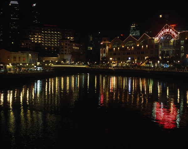 SINGAPORE, Cityscapes, Clarke Quay on the Singapore River. Waterside shops and restaurants illuminated at night with multi coloured lights reflected on the water