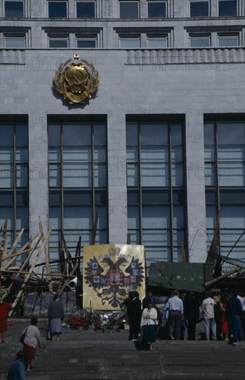 RUSSIA, Moscow, Parliament building with barricades made from pieces of wood and metal after an attempted coup. People standing on the steps next to the Coat of Arms of the Russian Federation emblem which depicts a double headed eagle.
