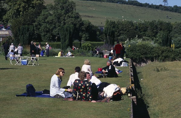 ENGLAND, East Sussex, Glyndebourne, Opera attendees enjoying picnics in the gardens during interval.