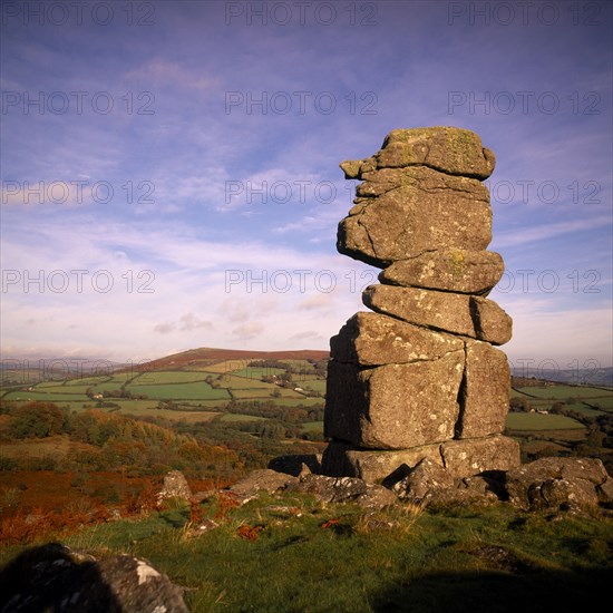 ENGLAND, Devon, Dartmoor, Bowerman’s Nose.  Dramatic granite tor shaped like face in profile with moorland landscape and hills beyond.  Bracken and trees in Autumn colours.