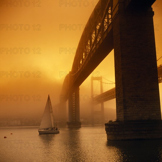 ENGLAND, Devon, Plymouth, Royal Albert Bridge designed by Brunel and finished in 1859.  Spans the River Tamar between Plymouth and Saltash. Yacht passing below.