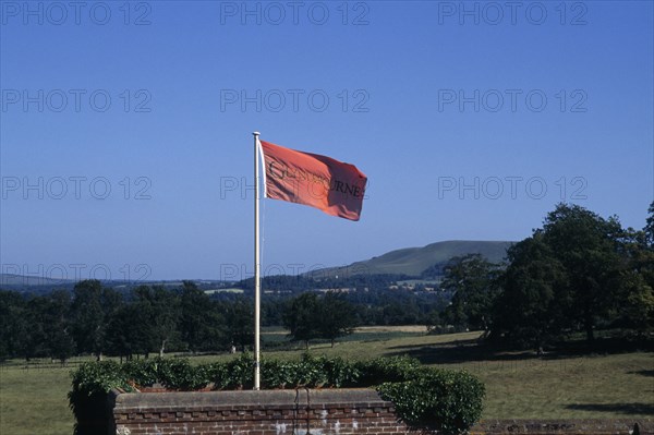ENGLAND, East Sussex, Glyndebourne, Red flag in the grounds of the country house and opera house looking out over green countryside