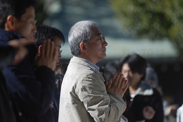 JAPAN, Honshu, Tokyo, "Jingumae - in front of Meijijingu shrine, gray haired man about sixty years old praying, New Years worship"