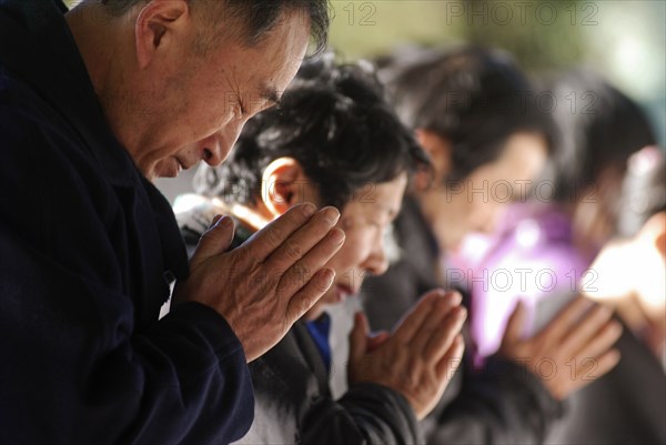 JAPAN, Honshu, Tokyo, "Jingumae - at Meijijingu shrine, line of New Years worshippers praying, in fore man over sixty years old"
