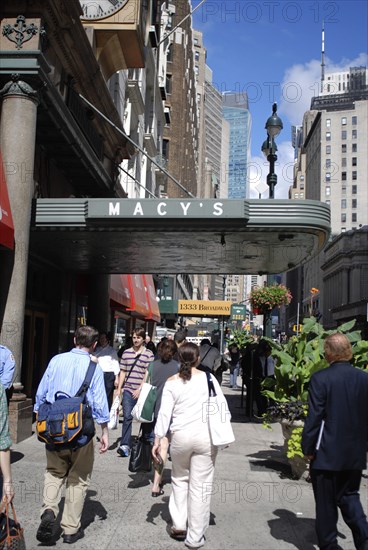 USA, New York, Manhattan, Broadway with people walking along the sidewalk outside the entrance to Macy's department store.