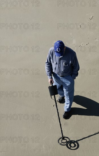 USA, Georgia, Tybee Island, Man using a metal detector on the beach.