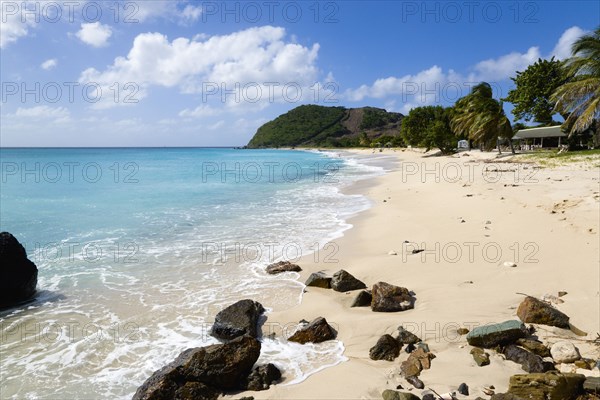 WEST INDIES, St Vincent & The Grenadines, Canouan, South Glossy Beach in Glossy bay with footprints in the sand and waves from the turqoise sea breaking on the shore.