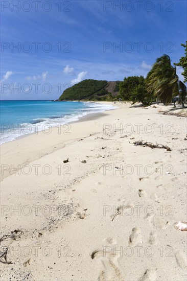 WEST INDIES, St Vincent & The Grenadines, Canouan, South Glossy Beach in Glossy bay with footprints in the sand and waves breaking on the shore.