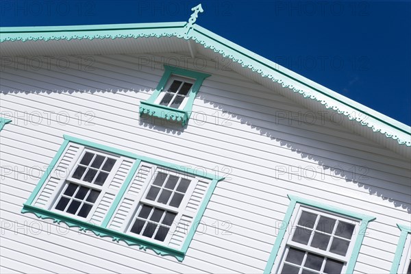 WEST INDIES, Grenada, Carriacou, Hillsborough Turqoise and white wooden clapperboard house detail against a clear blue sky.