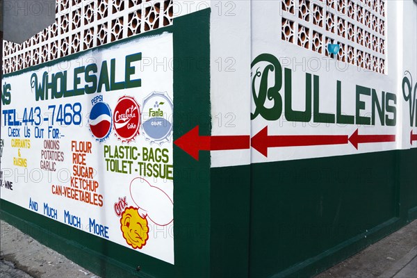 WEST INDIES, Grenada, Carriacou, Hillsborough The freshly painted walls of Bullens Wholesale shop advertising food and drink and household goods.