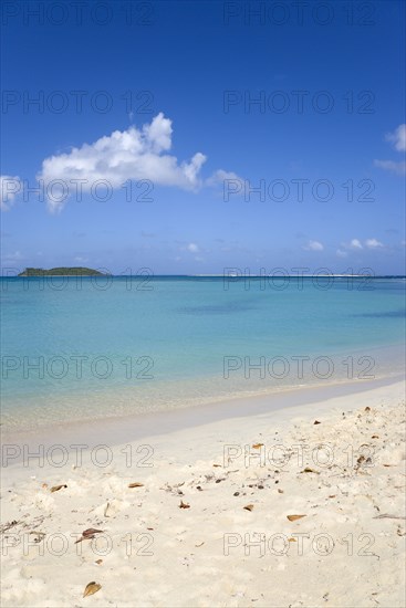 WEST INDIES, Grenada, Carriacou, Waves breaking on Paradise Beach at L'Esterre Bay with the turqoise sea and Sandy Island sand bar beyond.