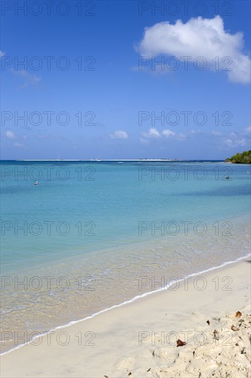 WEST INDIES, Grenada, Carriacou, Waves breaking on Paradise Beach at L'Esterre Bay with the turqoise sea and Sandy Island sand bar beyond.