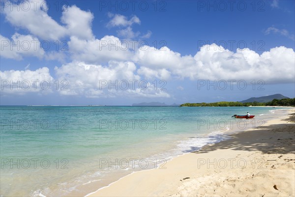 WEST INDIES, Grenada, Carriacou, Waves breaking on Paradise Beach at L'Esterre Bay with a fisherman beaching his boat and the turqoise sea and Sandy Island sand bar beyond.