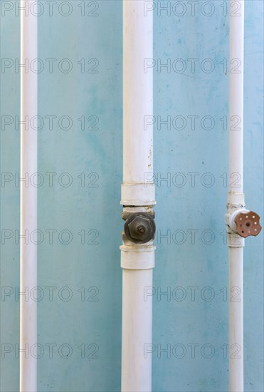 WEST INDIES, St Vincent & The Grenadines, Union Island, Three white pipes running down a turqoise painted wall in Clifton.