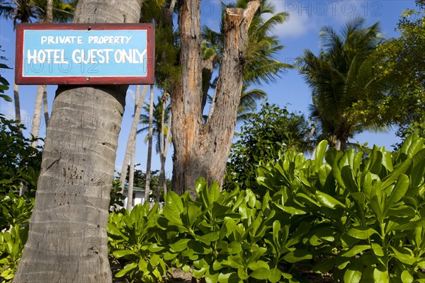 WEST INDIES, St Vincent & The Grenadines, Union Island, Sign attached to a coconut palm tree in the grounds of the Anchorage Yacht Club saying Private Property Hotel Guests Only.