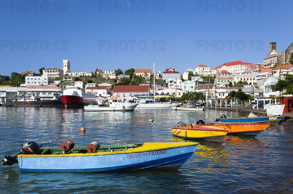 WEST INDIES, Grenada, St Georges, The Carenage in the capital with houses lining the hillside and colourful water taxis moored in the harbour.