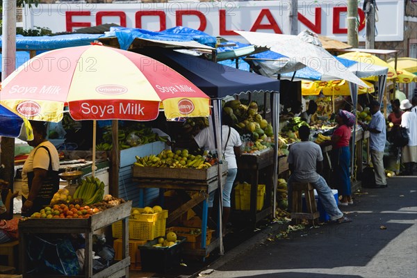 WEST INDIES, Grenada, St Georges, Busy fruit and vegetable stalls under umbrellas in Market Square outside Foodland supermarket.