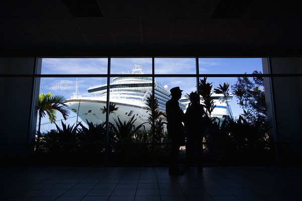 WEST INDIES, Grenada, St George, Tourists in the terminal building looking at the cruise ship liners Caribbean Princess and Aida Aura docked at the Cruise Ship Terminal in the capital St Georges.