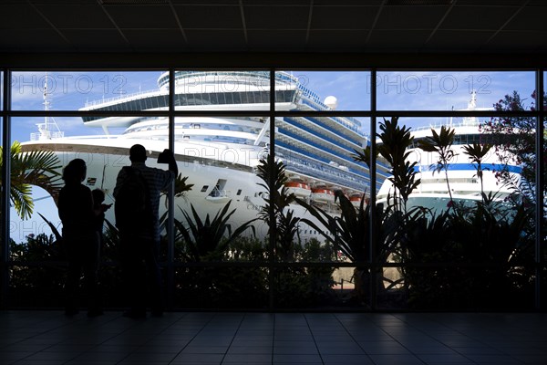 WEST INDIES, Grenada, St George, Tourists in the terminal building looking at the cruise ship liners Caribbean Princess and Aida Aura docked at the Cruise Ship Terminal in the capital St Georges.