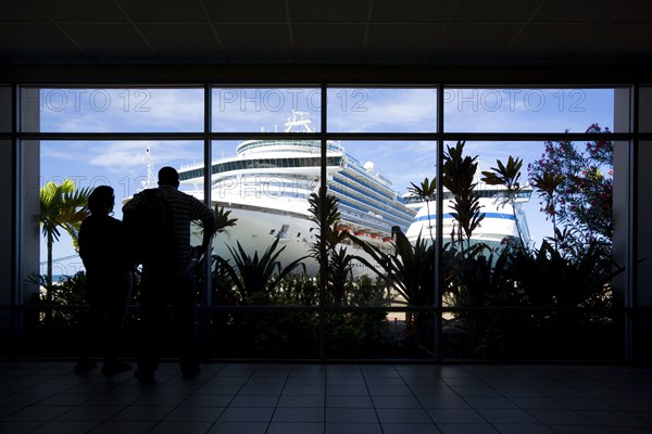 WEST INDIES, Grenada, St George, Tourists in the terminal building looking at the cruise ship liners Caribbean Princess and Aida Aura docked at the Cruise Ship Terminal in the capital St Georges.