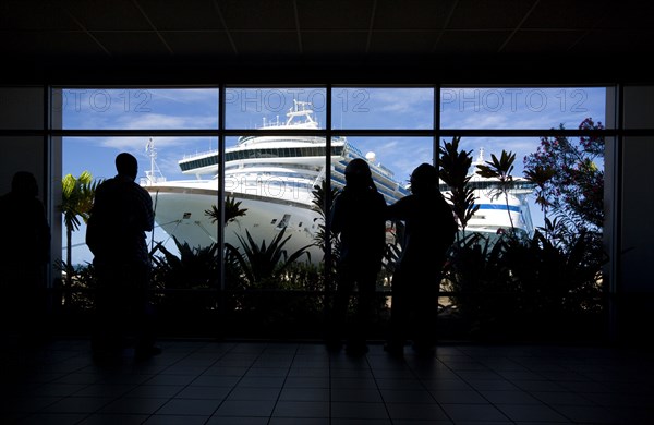 WEST INDIES, Grenada, St George, Tourists in the terminal building looking at the cruise ship liners Caribbean Princess and Aida Aura docked at the Cruise Ship Terminal in the capital St Georges.