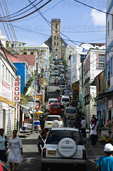 WEST INDIES, Grenada, St George, St Juille Street with overhead power cables busy with traffic and pedestrian shoppers leading to the hurricane damaged and roofless Roman Catholic Cathedral in the capital.