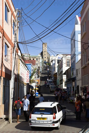 WEST INDIES, Grenada, St George, St Juille Street with overhead power cables busy with traffic and pedestrian shoppers leading to the hurricane damaged and roofless Roman Catholic Cathedral in the capital.