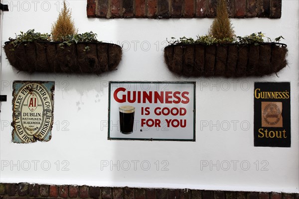 IRELAND, North, Belfast, "Cathedral Quarter, Commerical Court, Old metal Guinness signs decorating the exterior of the Duke of York Public House."