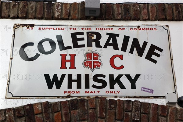 IRELAND, North, Belfast, "Cathedral Quarter, Commerical Court, Old Coleraine Whiskey metal sign decorating the exterior of the Duke of York Public House"