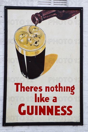IRELAND, North, Belfast, "Bank Square, Old metal Guinness sign decorating the exterior Kelly's Cellars Public House"