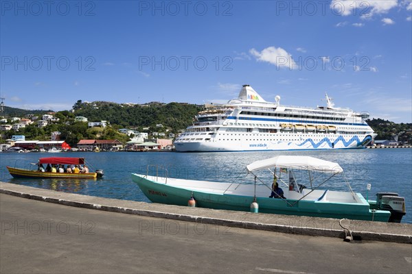 WEST INDIES, Grenada, St George, Cruise ship liner Aida Aura and local tourist boat moored on either side of the Carenage in the harbour with a full tourist boat approaching the dockside.