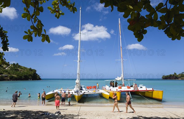 WEST INDIES, Grenada, St George, Tourists from cruise ships on BBC Beach in Morne Rouge Bay in the aquamarine sea on the beach and beside their day trip catamarans at the waters edge.