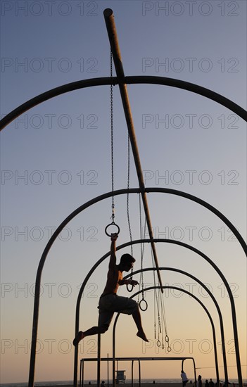 USA, California, Los Angeles, "Gymnast silhoutted on the rings, Santa Monica beach"