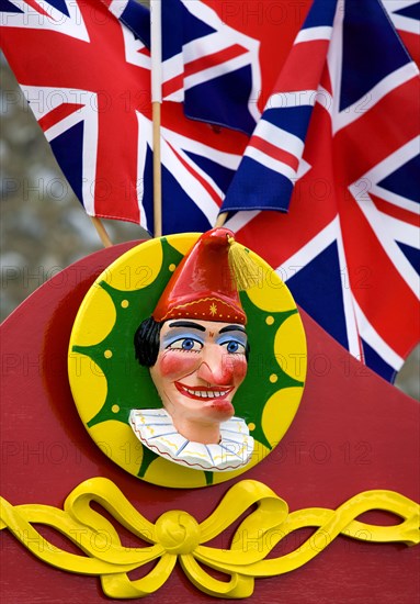 ENGLAND, West Sussex, Findon, Findon village Sheep Fair Bright red Punch and Judy stand with Union Jack flags and a carved image of Punch.