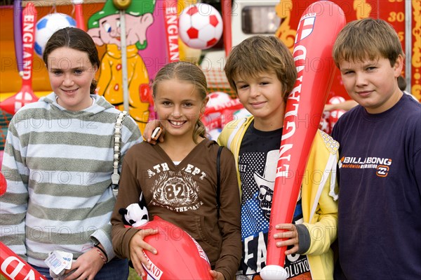 ENGLAND, West Sussex, Findon, Findon village Sheep Fair Two teenage boys and two girls holding prizes won at fairground stalls.