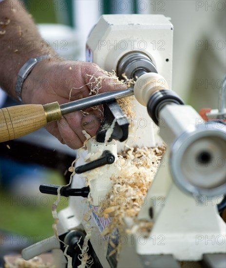 ENGLAND, West Sussex, Findon, Findon village Sheep Fair Man using a wood lathe with a chisel cutting into the spinning wood.