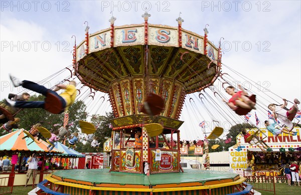 ENGLAND, West Sussex, Findon, Findon village Sheep Fair Children in motion riding on a swing carousel.