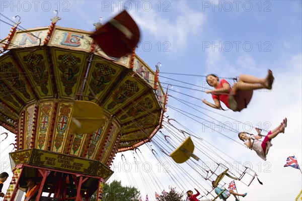 ENGLAND, West Sussex, Findon, Findon village Sheep Fair Children in motion riding on a swing carousel.