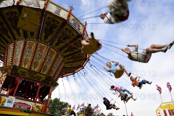 ENGLAND, West Sussex, Findon, Findon village Sheep Fair Children in motion riding on a swing carousel.