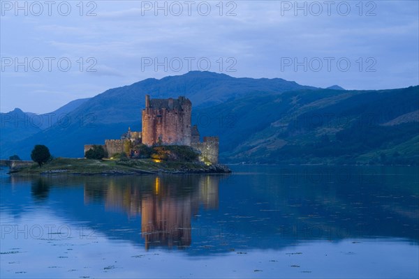SCOTLAND, Highlands, Dornie, "Eilean Donan Castle in Loch Duich, the most photographed castle in the world at night with reflection on still waters."