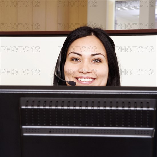 BUSINESS, Offices, Telesales, Portrait of a female customer service representative sitting in front of a computer and smiling.