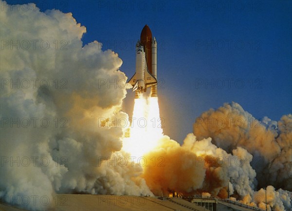 USA, Florida, Kennedy Space Centre, NASA Space Shuttle lifting off amidst thick white clouds of smoke and flames from rocket boosters.